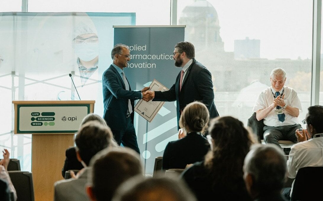 Two people shaking hands on a stage at an award ceremony